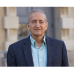 Jainendra Jain stands for a photo in a navy blue blazer and light blue button up.